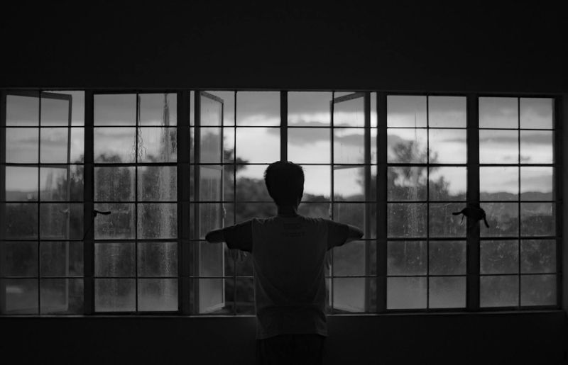 A person looking out a large window at a serene landscape.